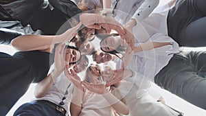 A group of high school students look through the shape of a circle created from their palms. The concept of friendly