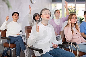 Group of high school students raising hands in auditorium
