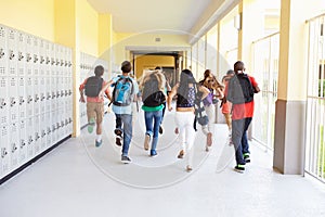 Group Of High School Students Running Along Corridor