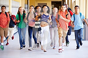 Group Of High School Students Running Along Corridor