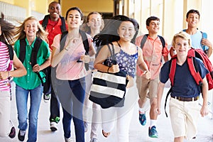 Group Of High School Students Running Along Corridor