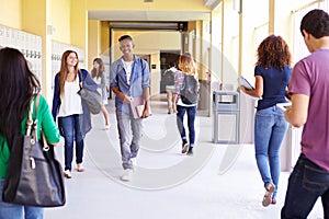 Group Of High School Students Walking Along Hallway