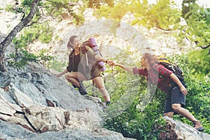 Group Hiker woman helping her friend climb up the last section of sunset in mountains. Traveler teamwork walking in outdoor lifest photo