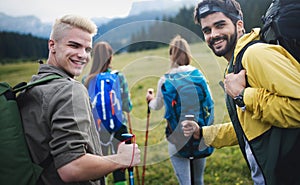 Group of hikers with backpacks and sticks walking on mountain. Friends making an excursion