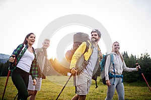 Group of hikers with backpacks and sticks walking on mountain. Friends making an excursion
