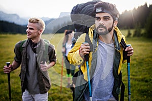 Group of hikers with backpacks and sticks walking on mountain. Friends making an excursion