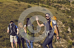 A group of hikers with backpacks are walking along the hill in the mountains in nature.