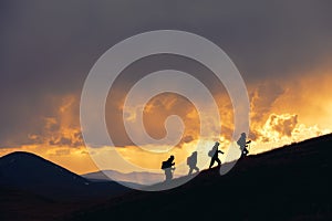 Group of hikers walks at majestic sunset in mountains