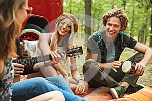 Group of hipsters travelers laughing, and playing guitar near vi