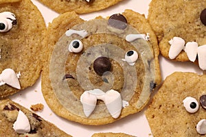A group of homemade, imperfect, chocolate chip cookies, each with a friendly face created out of candy and marshmallows