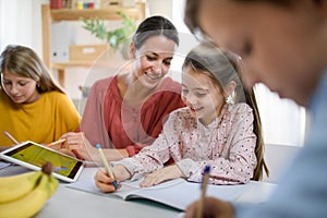 Group of homeschooling children with teacher studying indoors, coronavirus concept.