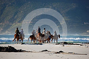 Horse riders at the beach with mountains in South Africa, Cape Town