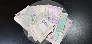 Hryvnia banknotes of various merits spread on black table photo
