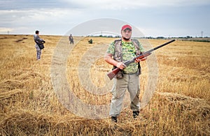 Group of hunters with a guns moving through the field