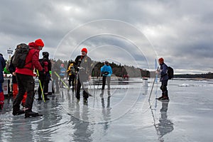 Group of ice skaters on wet melting ice with deep puddles.