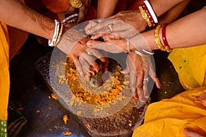 Group of Indian women holding a stone peace of mortar for making turmeric paste for wedding ceremony. Its a rituals of traditional