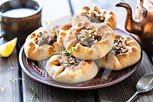 Group of individual pies with meat and potato - vak balish. Tatar traditional pies. Wooden background