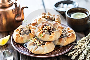 Group of individual pies with meat and potato - vak balish. Tatar traditional pies. Wooden background
