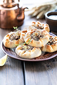 Group of individual pies with meat and potato - vak balish. Tatar traditional pies. Wooden background