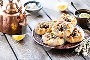 Group of individual pies with meat and potato - vak balish. Tatar traditional pies. Wooden background