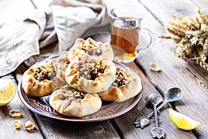 Group of individual pies with meat and potato - vak balish. Tatar traditional pies. Wooden background