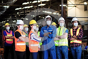 Group of industrial foreman and worker team consist of Technicians, Engineers and factory Manager wearing helmet and surgical mask