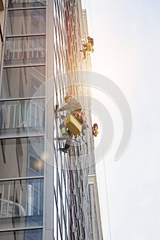 Group Industrial mountaineering workers in uniform washing exterior building glazing