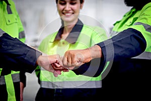 Group of industrial women men staff engineer worker joining fists together at factory workplace with smiling beautiful woman