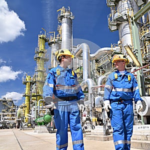 Group of industrial workers in a refinery - oil processing equipment and machinery