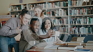 Group of international students have fun smiling and making selfie photos on smartphone camera at university library