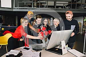 Group of international students or workers in loft office clinking cups of coffee, six colleagues of modern work co