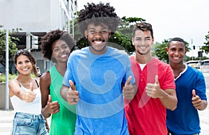 Group of international young adults showing thumbs in city