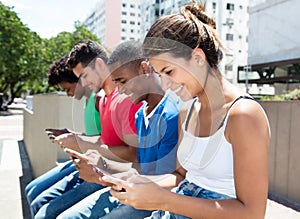 Group of international young adults typing message at phone