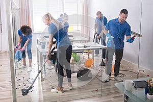 Group Of Janitors Cleaning Office With Cleaning Equipment