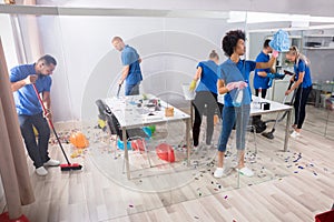 Group Of Janitors Cleaning Office With Cleaning Equipment