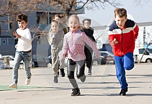 Group of joyful children running down the city street