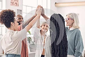 Group of joyful diverse businesspeople giving each other a high five in an office at work. Business professionals having