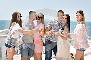 A group of joyful friends relaxing on a vacation. Pretty girls and strong men on a blue sky background. Friendship