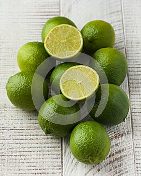 A group of juicy ripe limes on a white wooden background. Whole and cut in half limes.