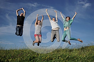 Group of jumping people on grean meadow