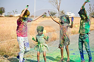 Group of Kids with colors applied dancing during holi festival celebration - Concept of joy and cheerful celebration