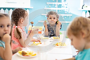 Group of kids eating healthy foo in kindergarten