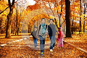 Group of kids go to school in autumn park