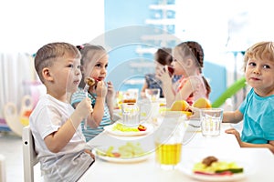 Kids have a lunch in daycare centre. Children eating healthy food in kindergarten photo