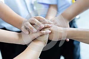 Group of kids joining hands Together , Team work or unity. Children putting hands together outdoors