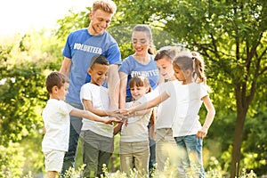 Group of kids joining hands with volunteers