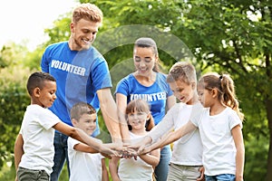 Group of kids joining hands with volunteers