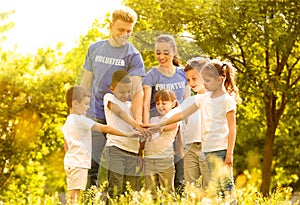 Group of kids joining hands with volunteers in park