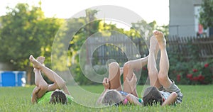 Group of kids lying on grass and having fun on a sunny day. two little boys and girl are smiling and rolling over on the