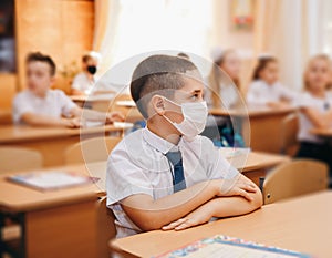 Group of kids in masks for coronavirus prevention in school classroom